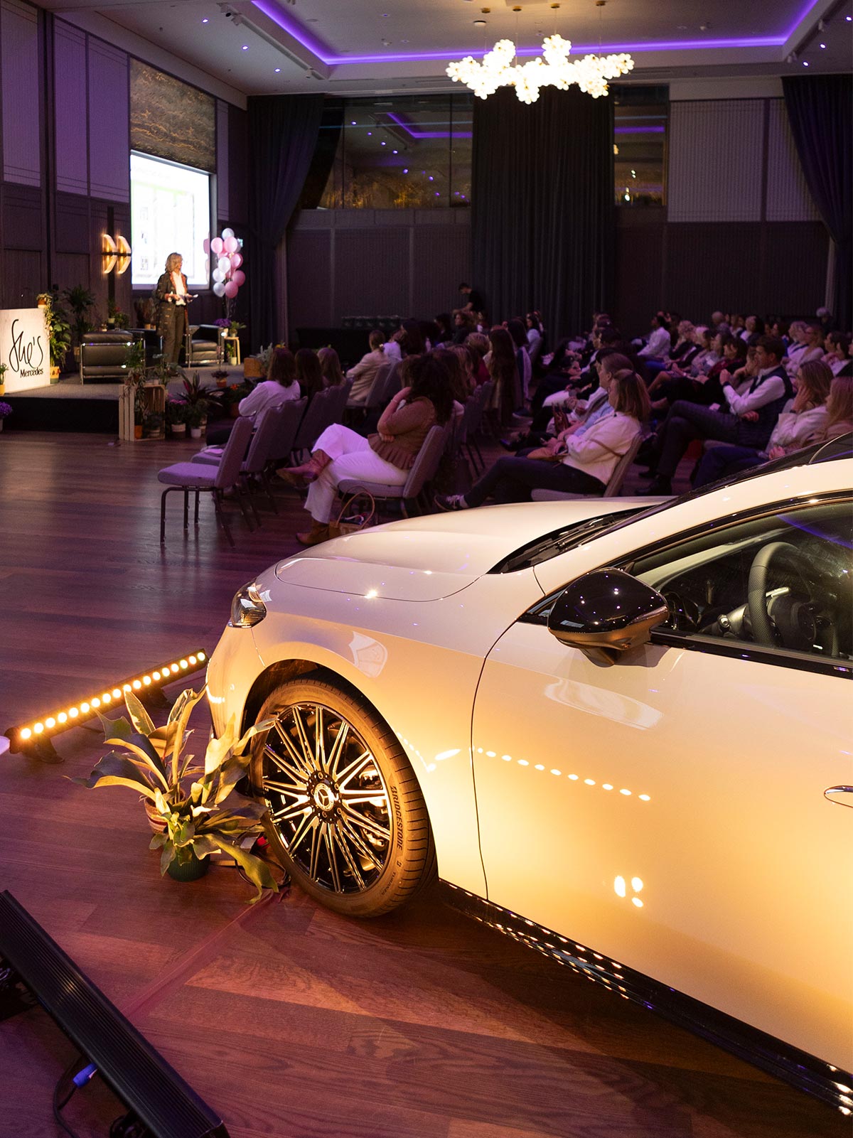 Eventsaal Eventsaal mit Gästen, Keynote-Speakerin und weissem Mercedes.