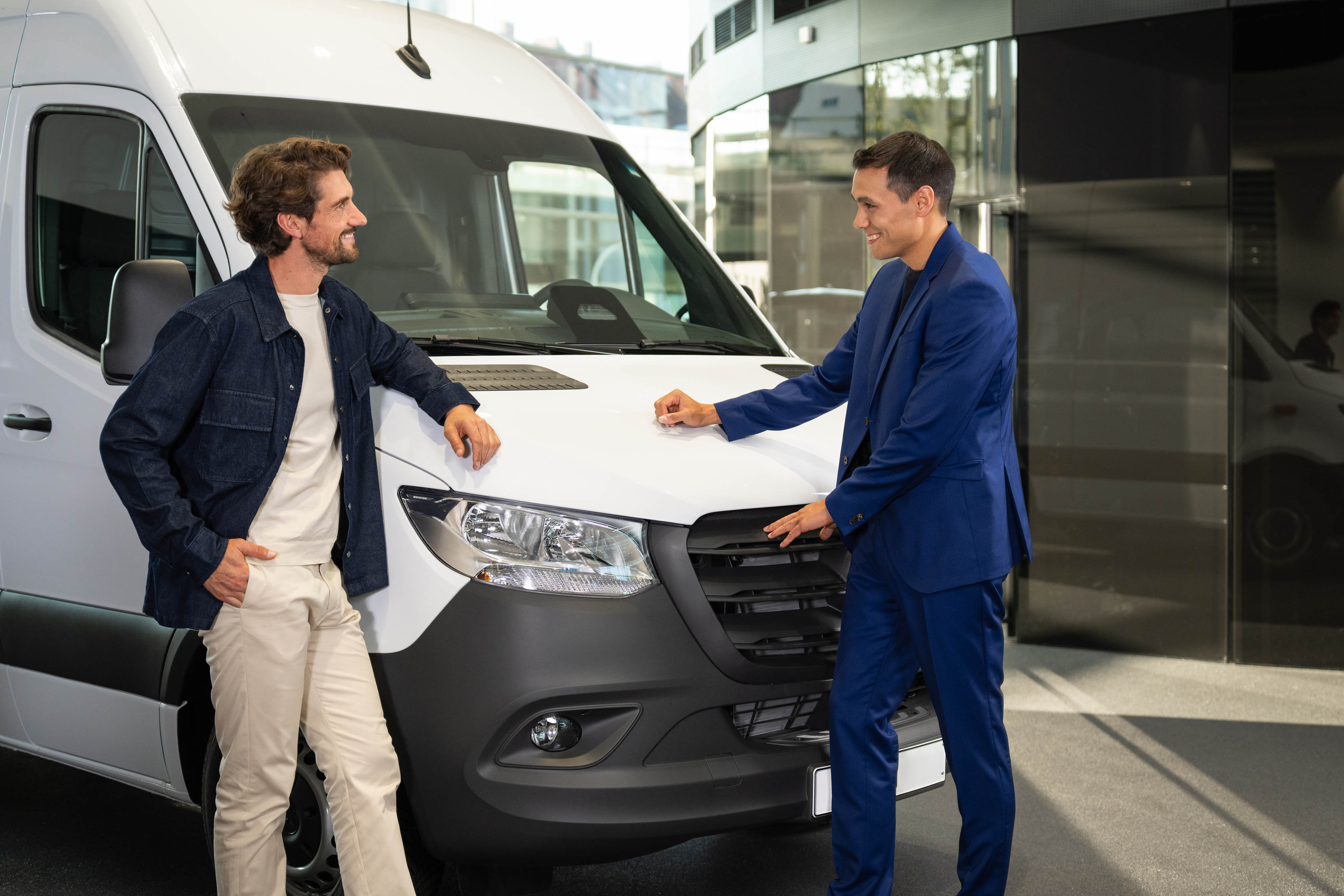 Leasingangebote für Mercedes-Benz Occasionen Zwei Personen lehnen sich an einen Mercedes-Benz Van und unterhalten sich.