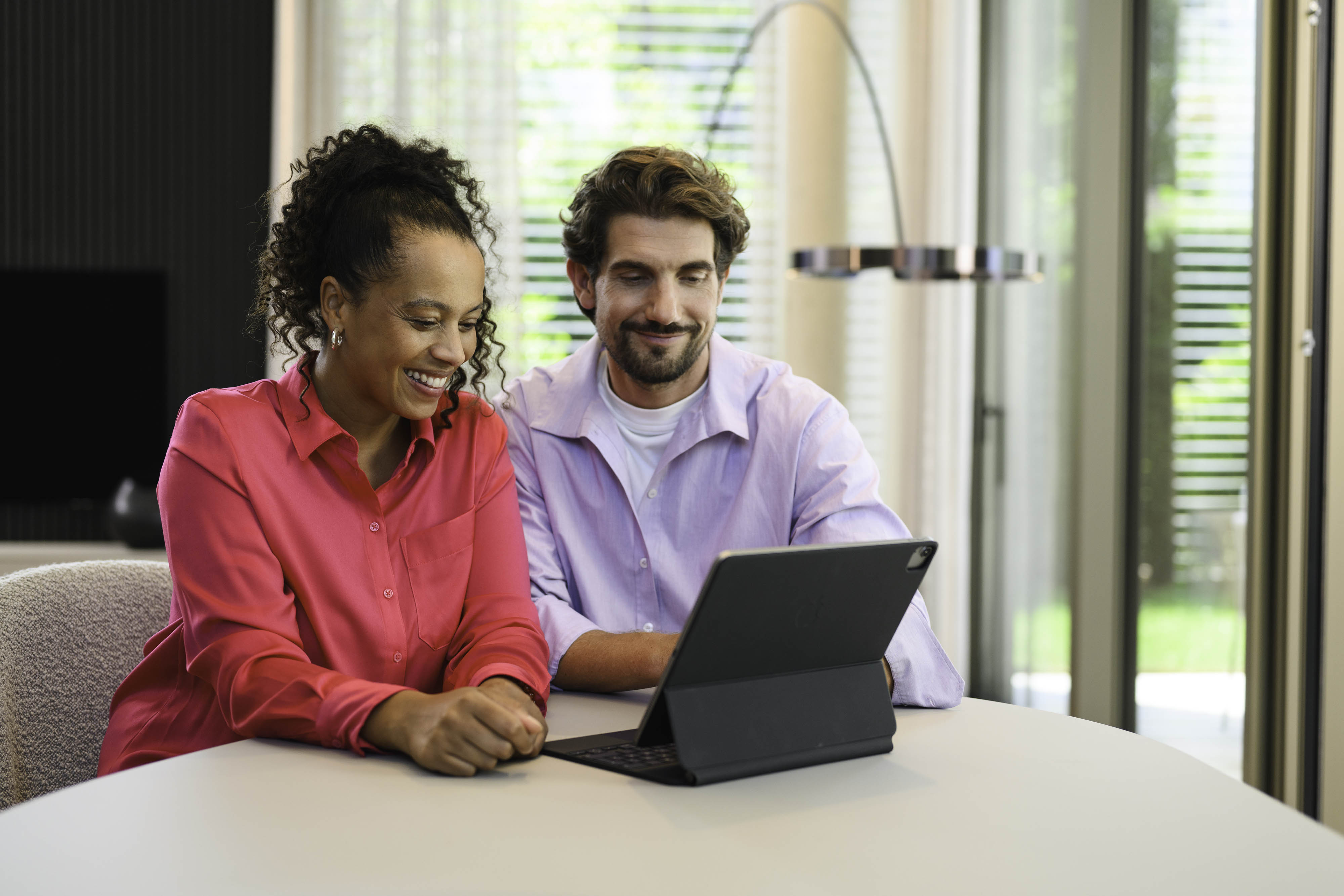 Portail client Mercedes-Benz Finance Deux personnes sont assises à une table et regardent un appareil mobile.