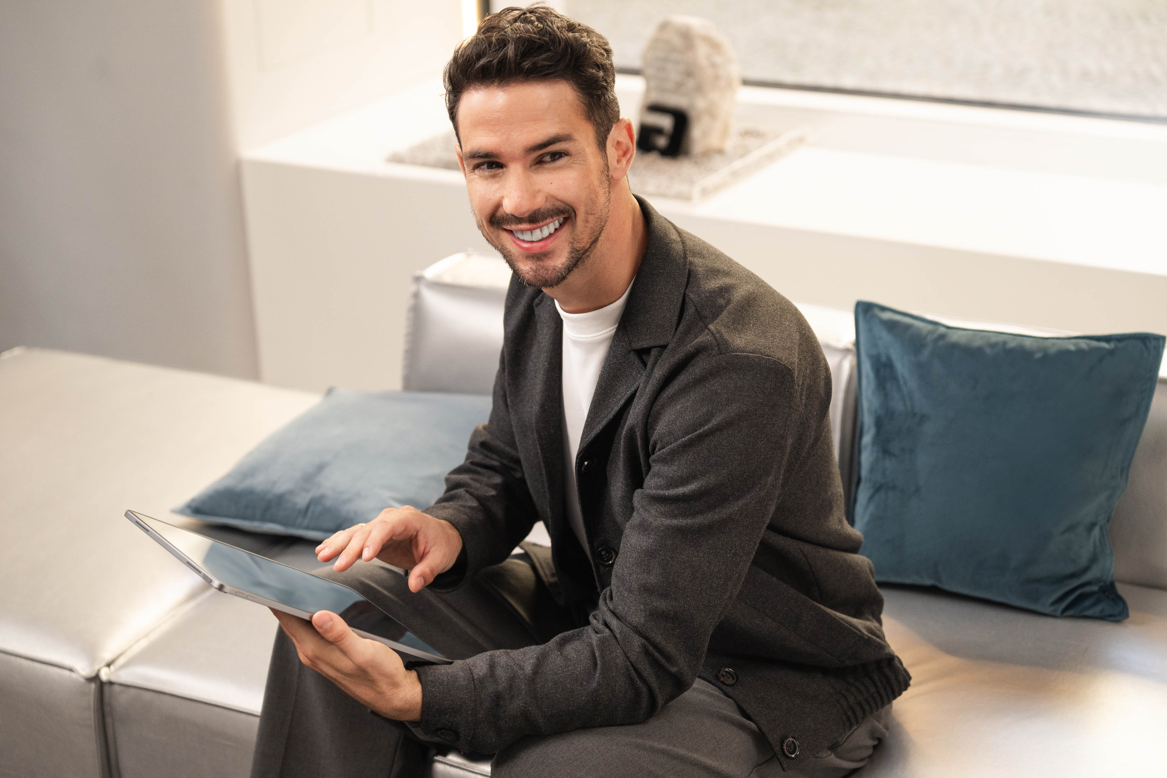 Mercedes-Benz Rent für Ihren Mercedes-Benz Eine Person, die auf einem Sofa sitzt und ihr Mobilgerät nutzt.