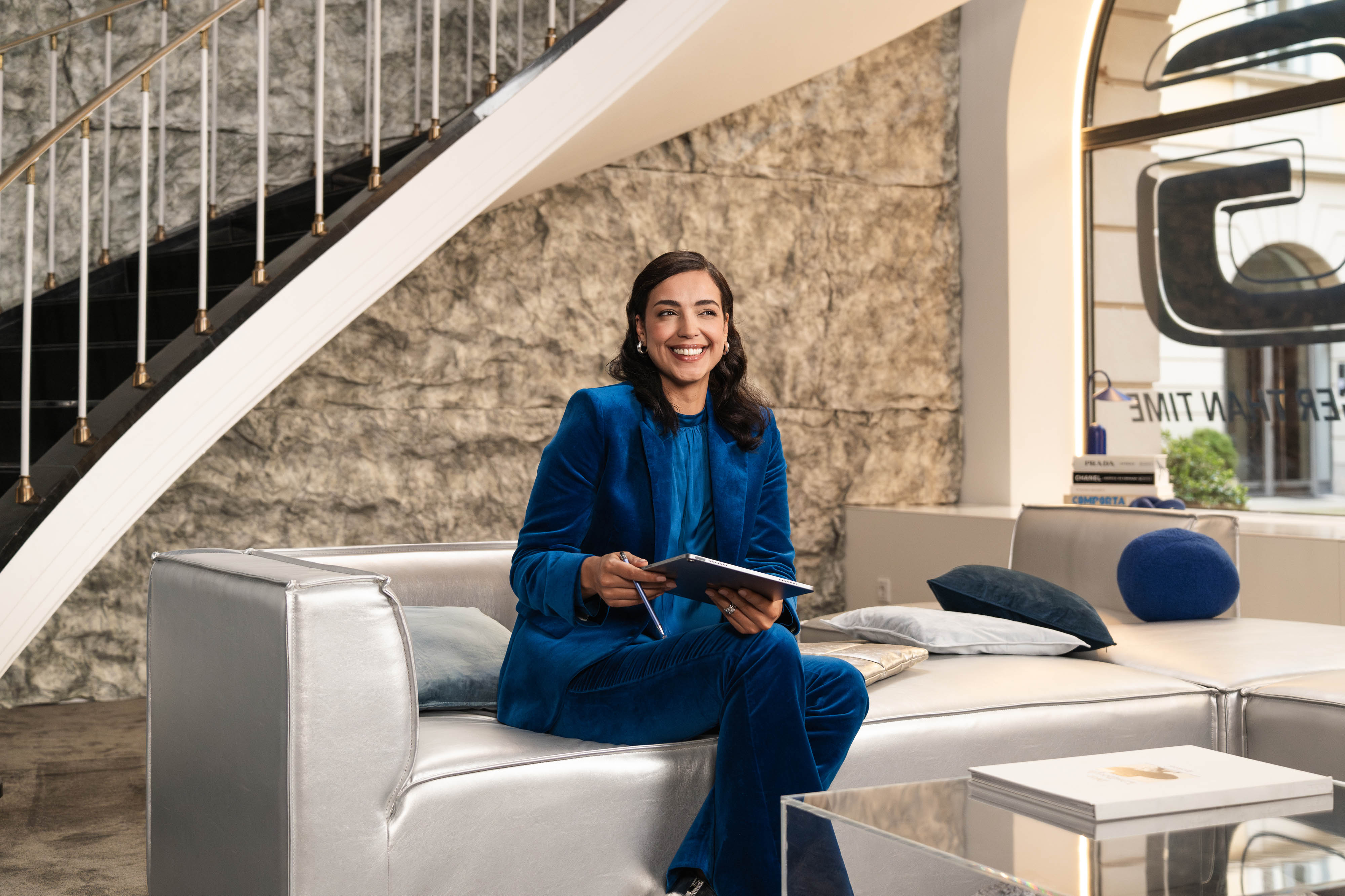 Vorteile von Mercedes-Benz Rent Eine Person sitzt auf einem Sofa und hält ein mobiles Gerät in der Hand.