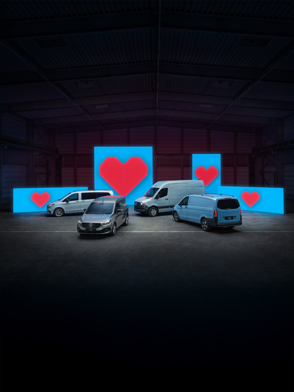Verschiedene Van-Elektromodelle stehen vor blauen Leuchtwänden mit je einem roten Herz. Aktuelles Leasing-Angebot für Elektro-Van.