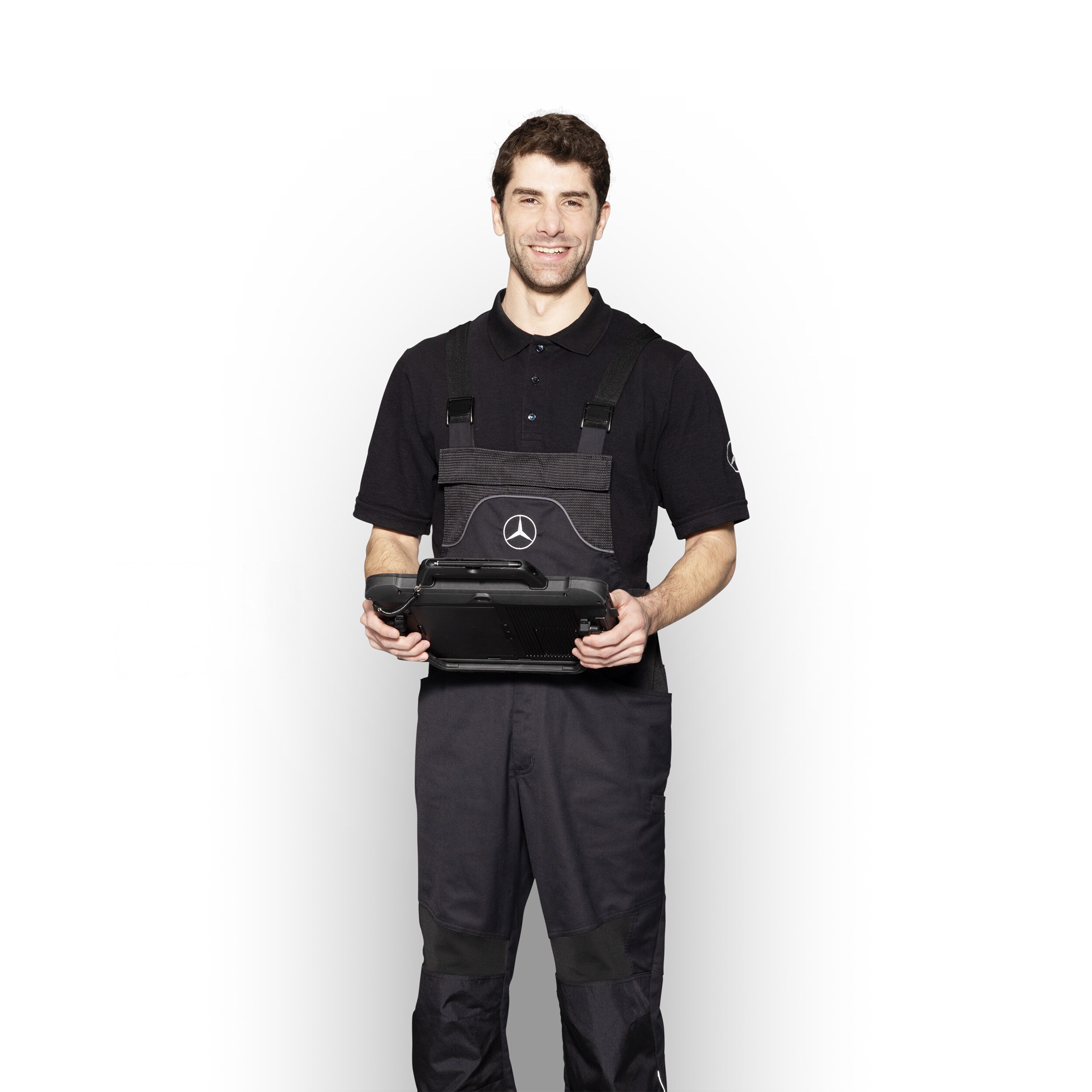 Aperçu des services Mercedes-Benz Mécanicien Mercedes-Benz en tenue de travail, tenant une tablette prête pour le signalement des dommages.